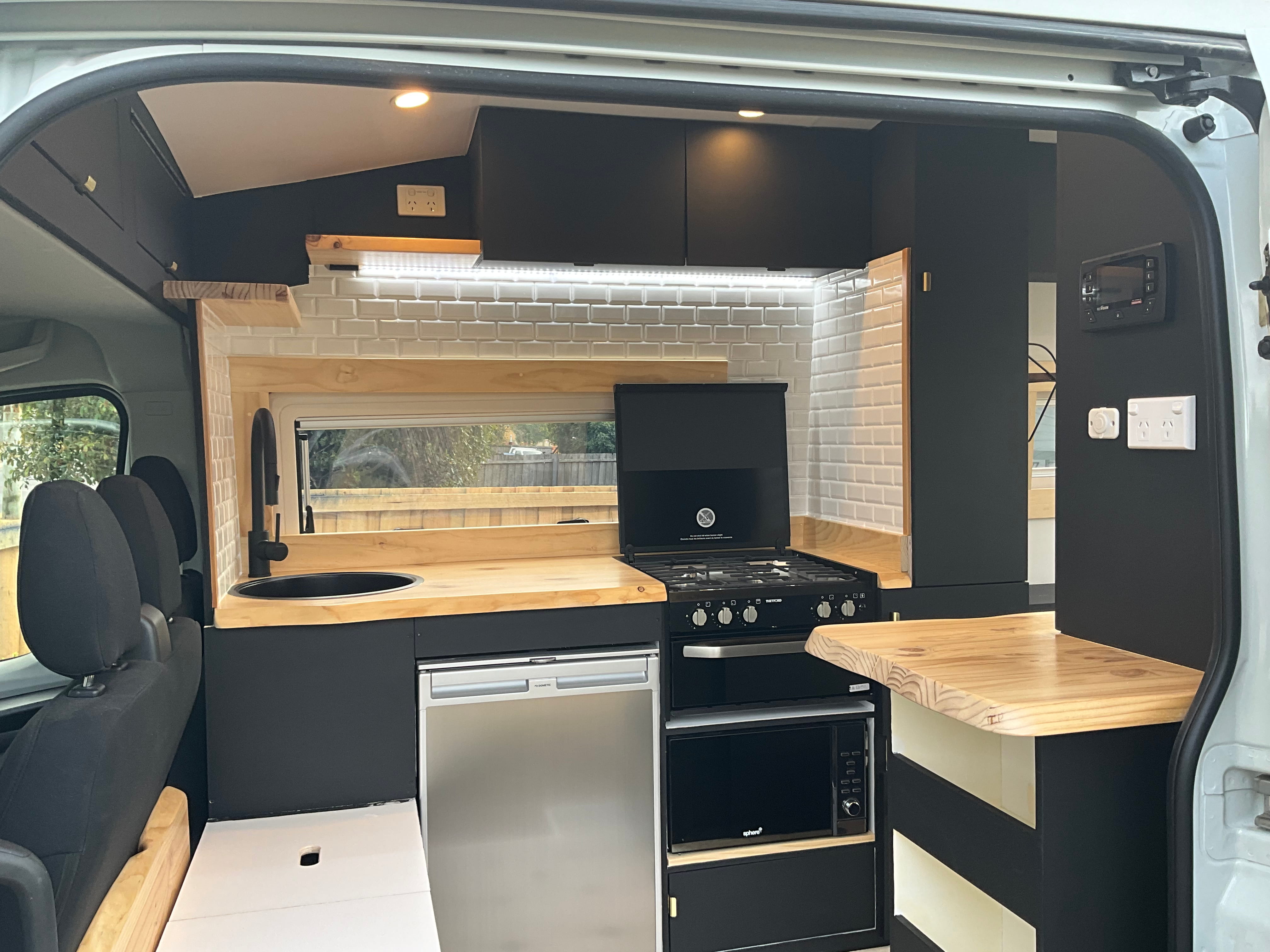 Custom van kitchen with timber benchtop and tiled splashback